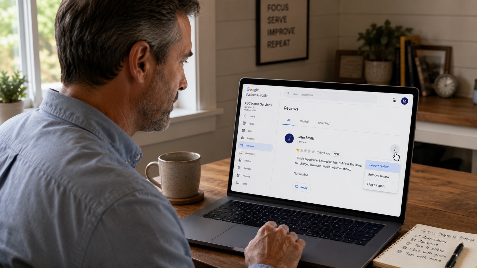 Small business owner at a home office looking at a Google Business Profile management view with the cursor hovering over the Report review option in a three-dot menu next to a 1-star review